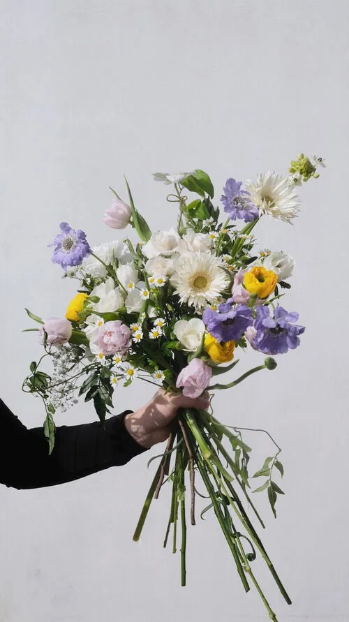 Floral arrangement designed by FLWR London featuring purple, white, green, and yellow flowers